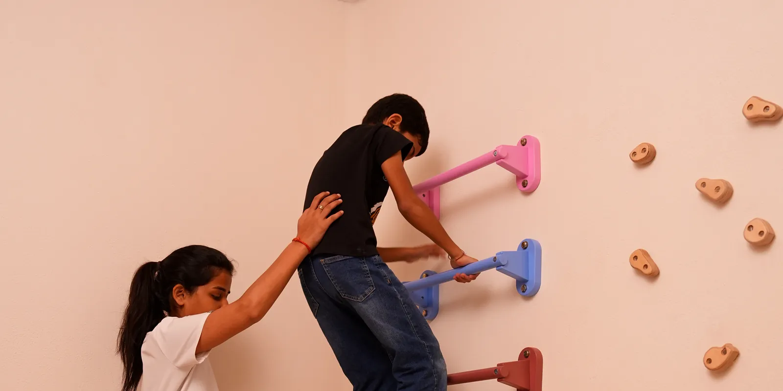 Practitioner guiding a child up the climbing wall